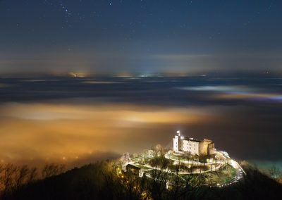 Das Hambacher Schloss über der vom Nebel bedeckten Rheinebene bei Nacht